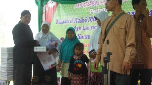 Ketua RW 06 Kel. Jatiraden, Jatisampurna, Haryanta (kiri) memberikan santunan kepada yatim dan dhuafa saat peringatan Maulid Nabi (dok. Mugi/KM)