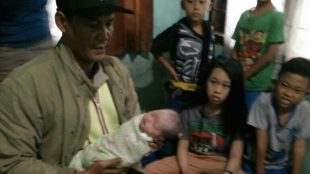 Petugas Kepolisian menggendong bayi perempuan yang ditemukan oleh warga Kelurahan Pabuaran, Cibinong, dalam keadaan hidup. (dok. KM)