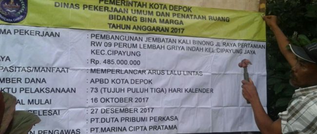 Pelaksana memasang papan proyek di lokasi pembangunan Jembatan Kali Binong, Depok, 10/12 (dok. KM)