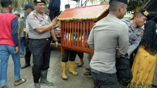 Kasat Sabhara AKP Zulkifli bersama personil Polres Aceh Utara membaws barang bawaan milik pengantin untuk diantarkan ke rumah mampelai wanita, dalam genangan air dengan kondisi jalan yang sulit dilalui, Kamis 4/1 (dok. KM/Ist/Raz)