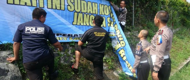 Anggota Polres Bogor memasang spanduk himbauan keselamatan berkendara di Jl. Raya Puncak, Rabu 6/6 (dok. KM)