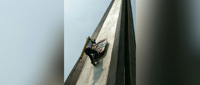 Pemanjat menaiki Tugu Kujang, Kota Bogor, untuk mencuci kujang atau 