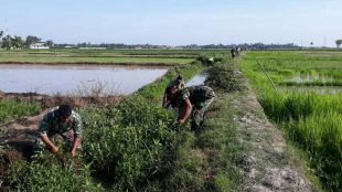 Babinsa dari jajaran Koramil Langsa Timur membersihkan saluran irigasi, Selasa 14/8 (dok. KM)
