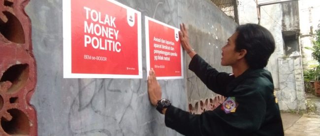 Seorang aktivis BEM Se-Bogor memasang stiker tolak money politics, Selasa 16/4/2019 (dok. KM)